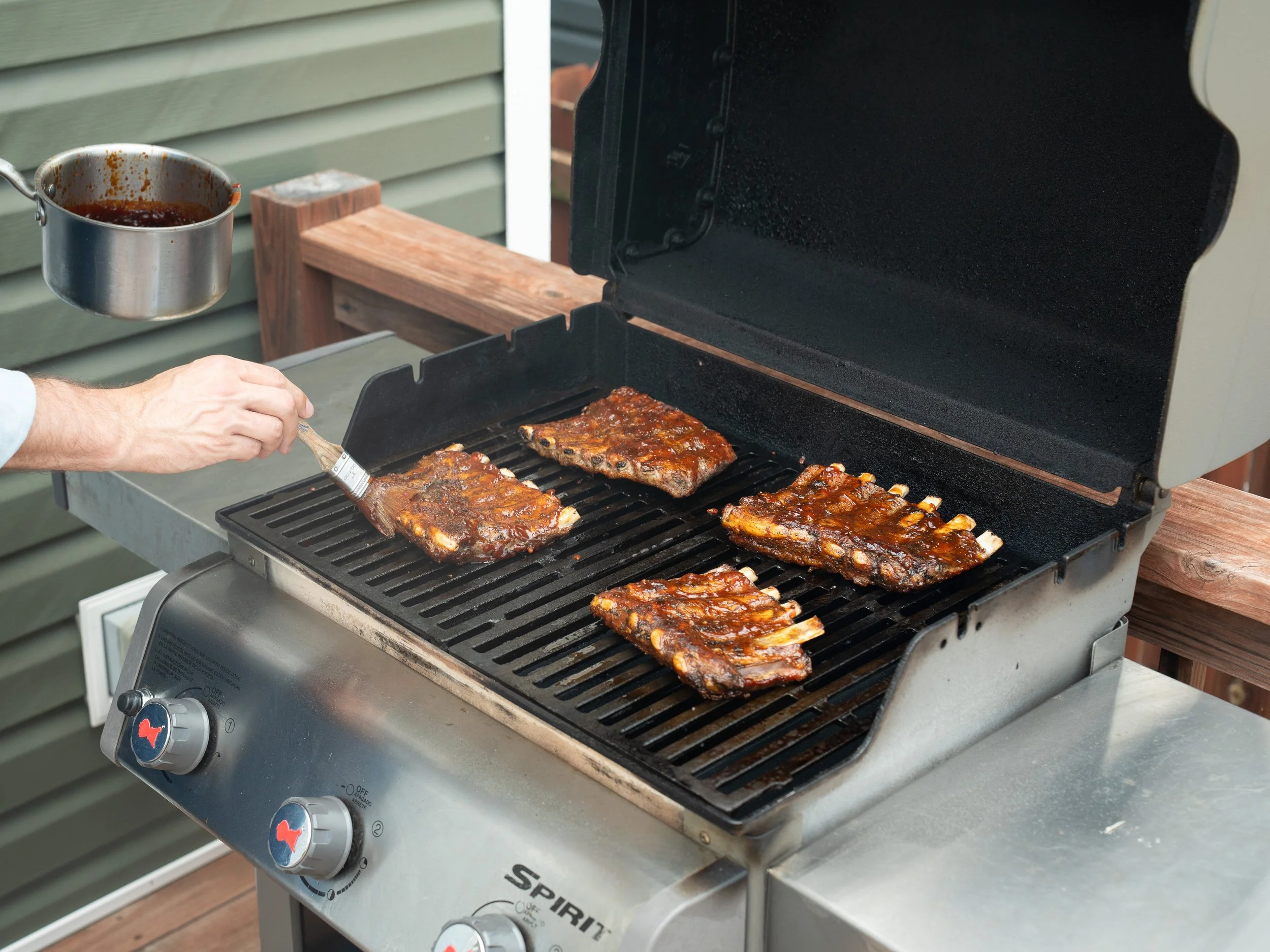 brusing bqq sauce onto ribs on grill