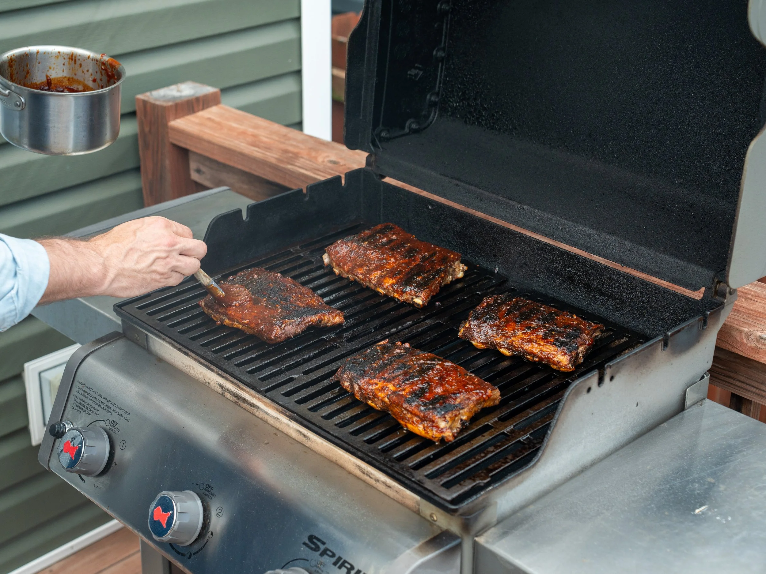 brushing grilled ribs with bbq sauce