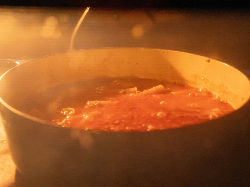 uncovered rigatoni pasta submerged in tomato sauce in oven