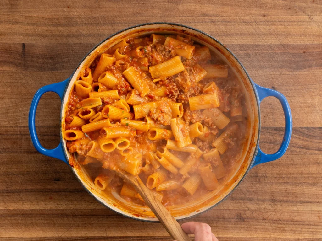 stirring rigatoni pasta with wooden spoon