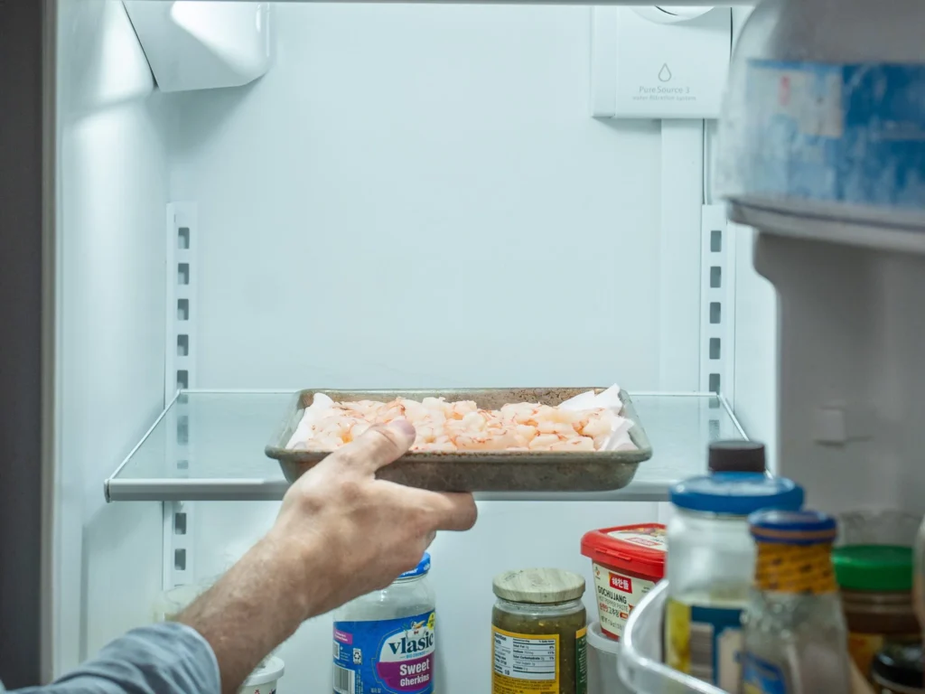 placing cooked shrimp in refrigerator on towel lined tray