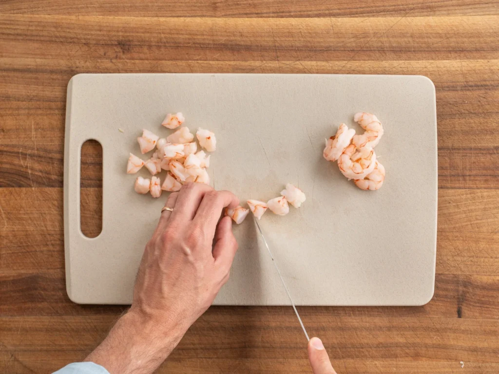 slicing shrimp on cutting board with knife