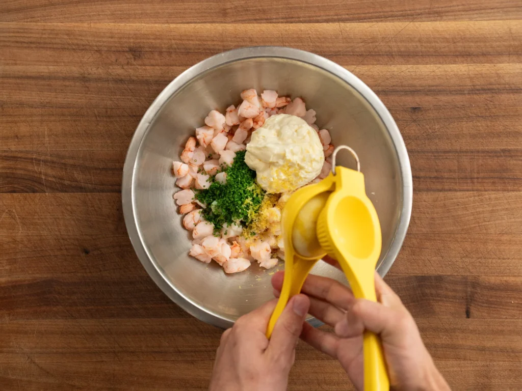 adding lemon juice to bowl of shrimp mayonnaise chives