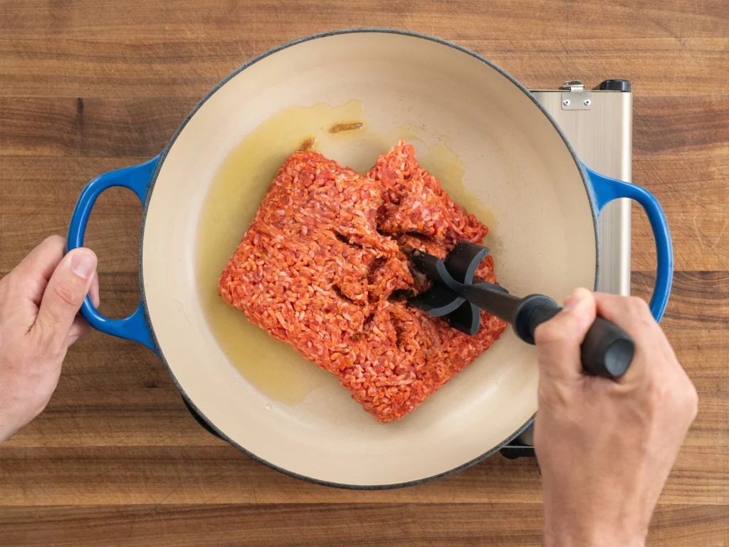 breaking apart ground pork with black meat chopper