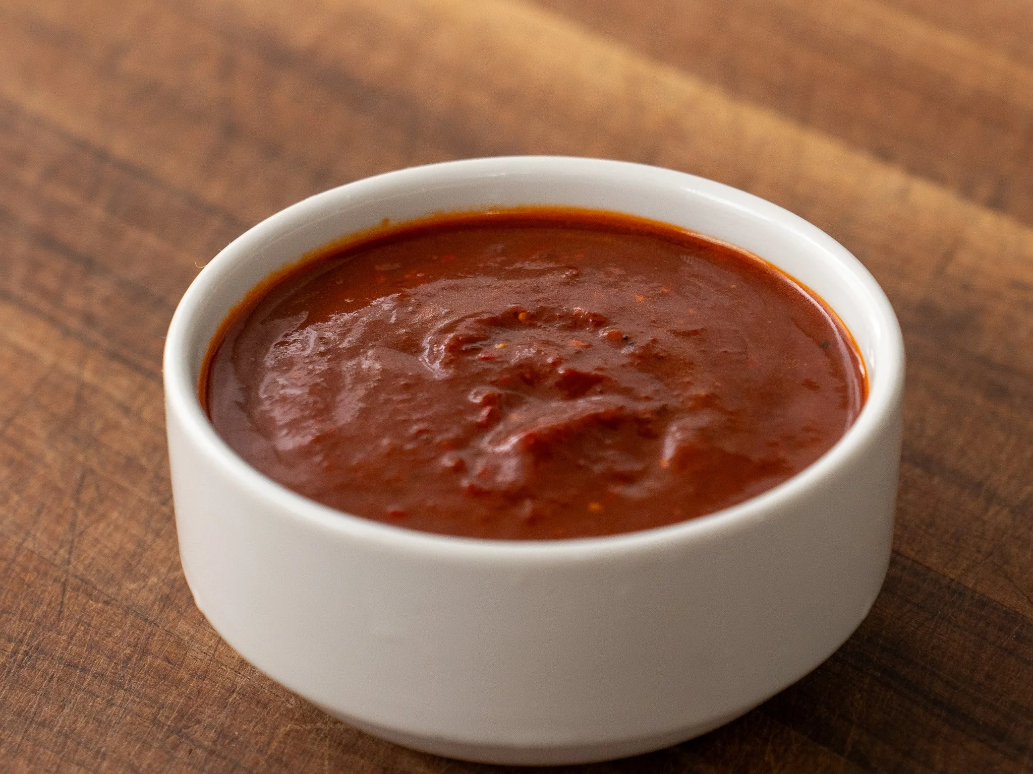 small white bowl filled with dark red salsa taquera