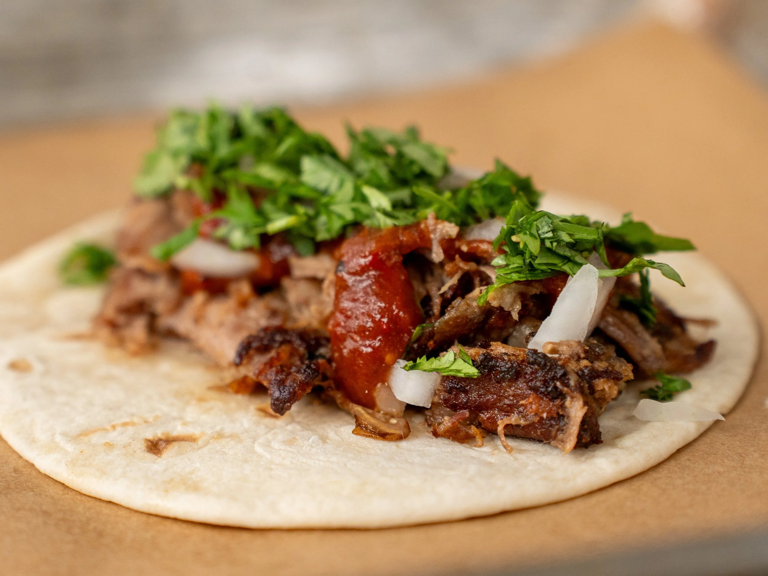 close up of pork carnitas taco with crispy pork red salsa onion cilantro