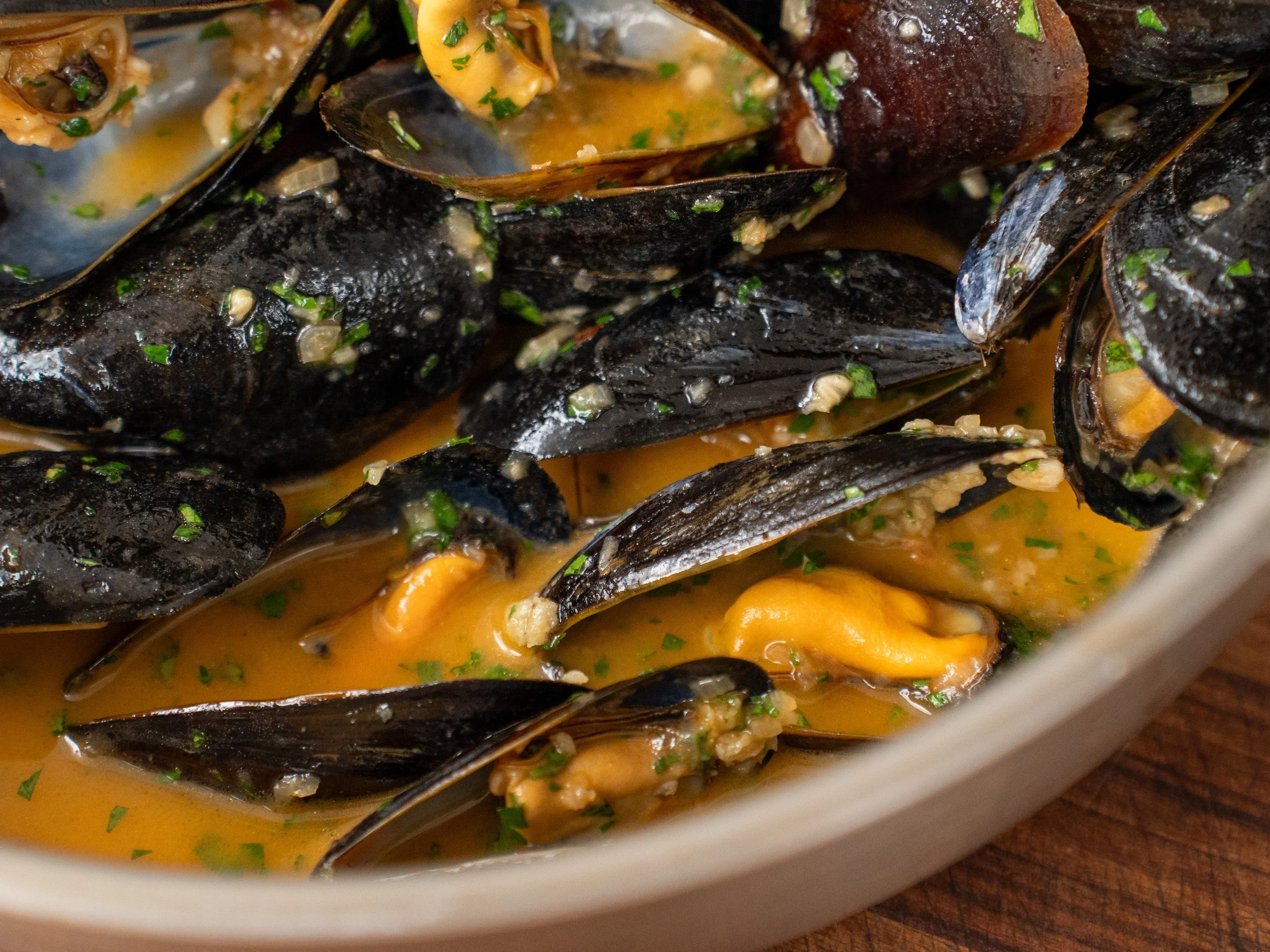 close up of cooked mussels in white wine sauce