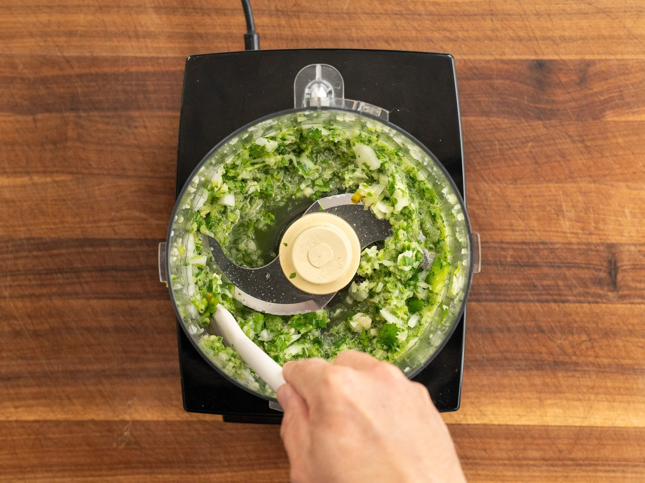 overhead shot of onion jalapeno cilantro chopped in food processor