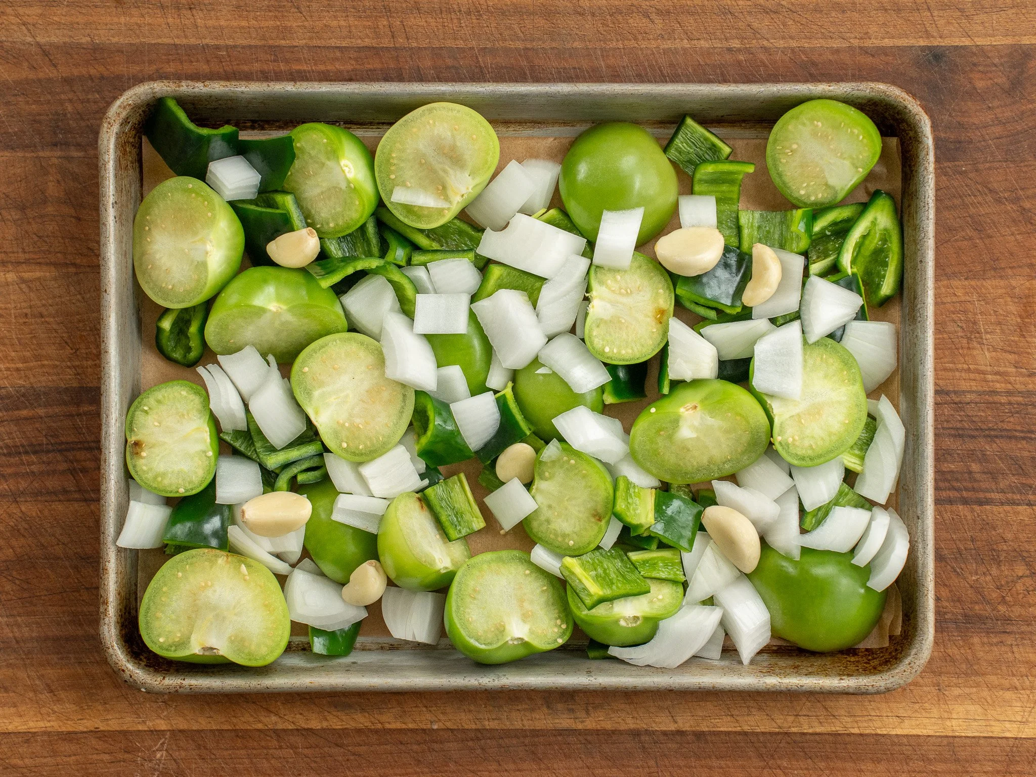tomatillos onions poblanos garlic on a sheet tray