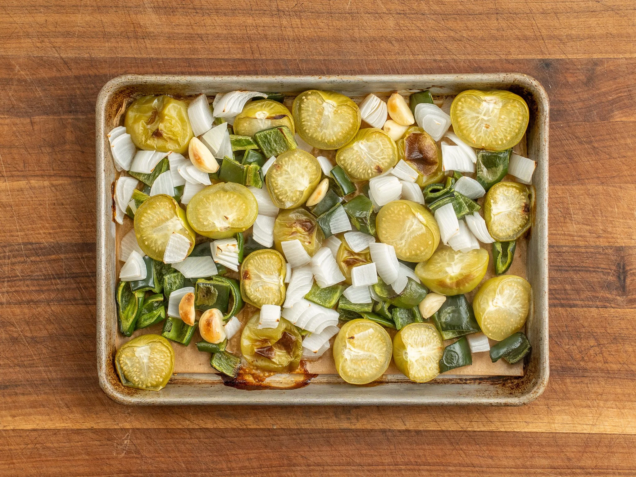 roasted tomatillos onions poblano peppers and garlic on a sheet tray