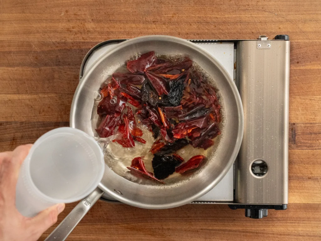 adding water to sauce pan of dried chiles 