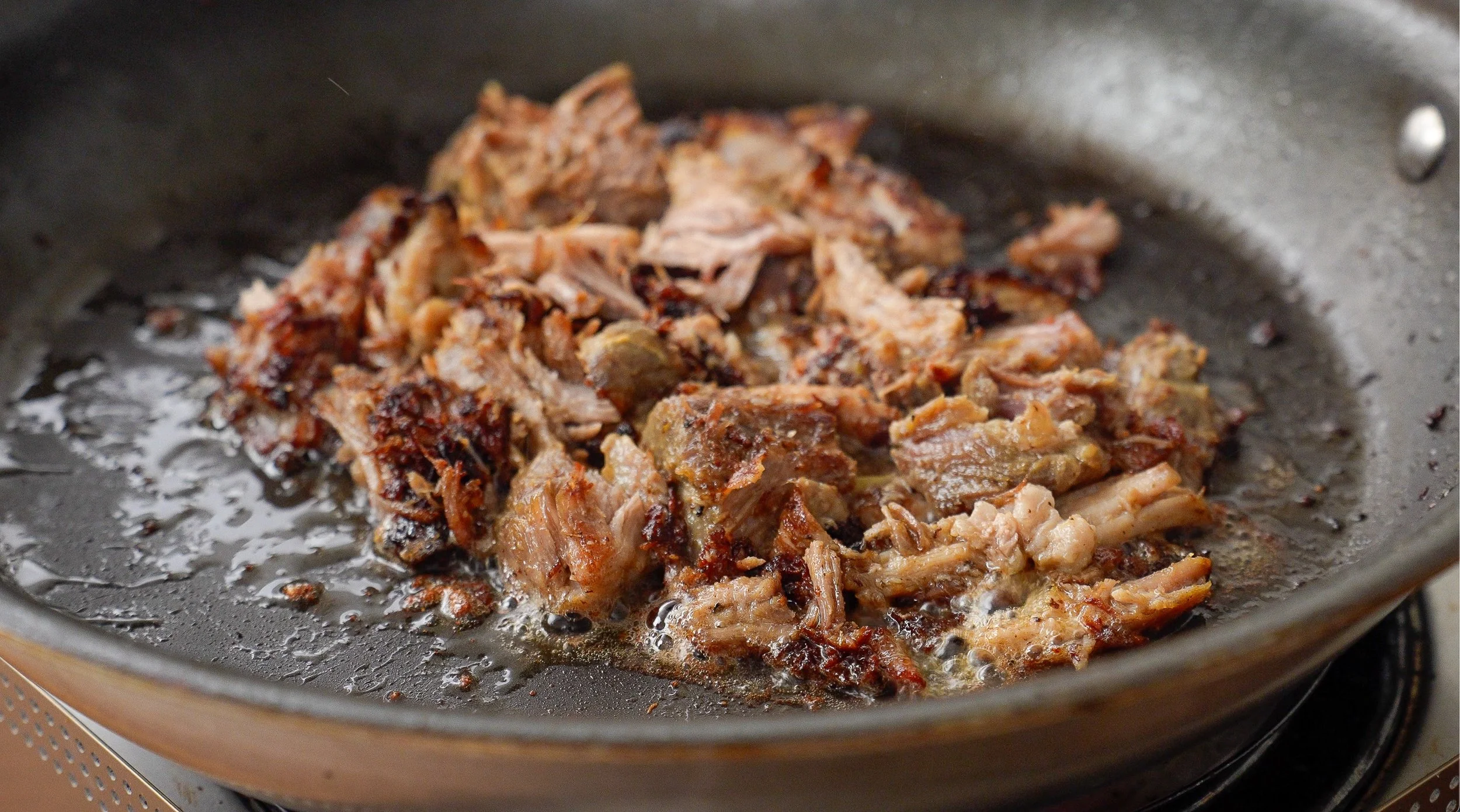 pork carnitas sizzling in nonstick pan