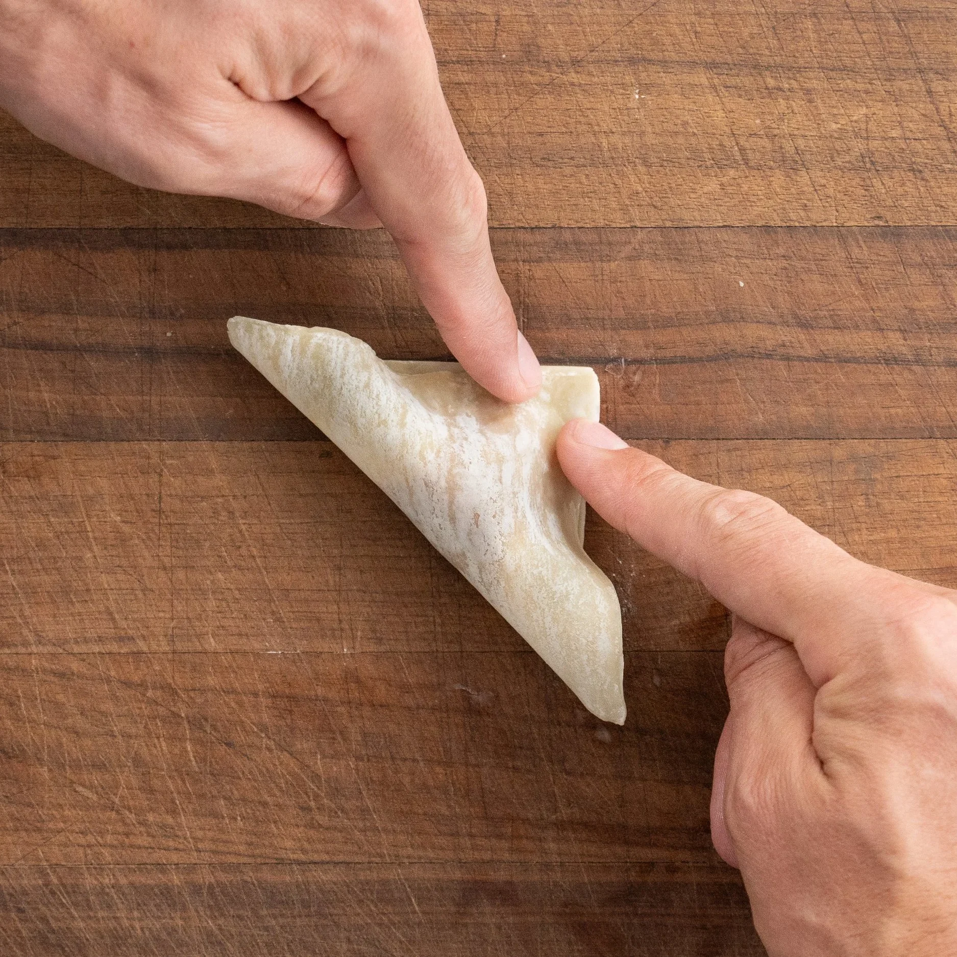 hands folding wonton wrapper over itself into a triangle