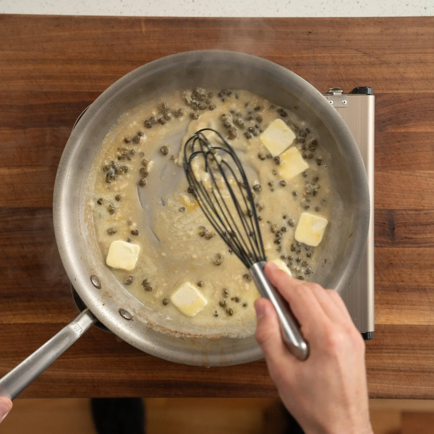 whisking butter into white wine caper sauce