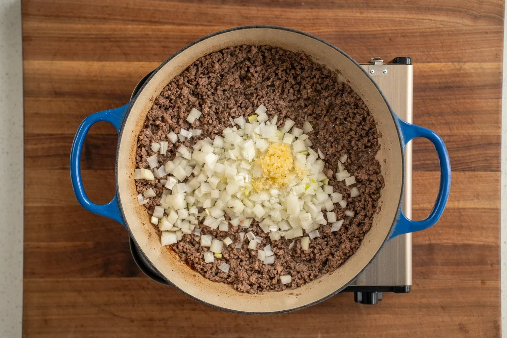sautéeing onions and garlic in a blue dutch oven