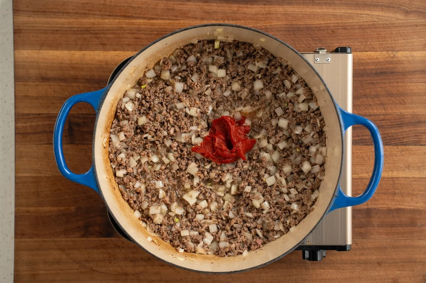 tomato paste in a pot of cooked beef and onions