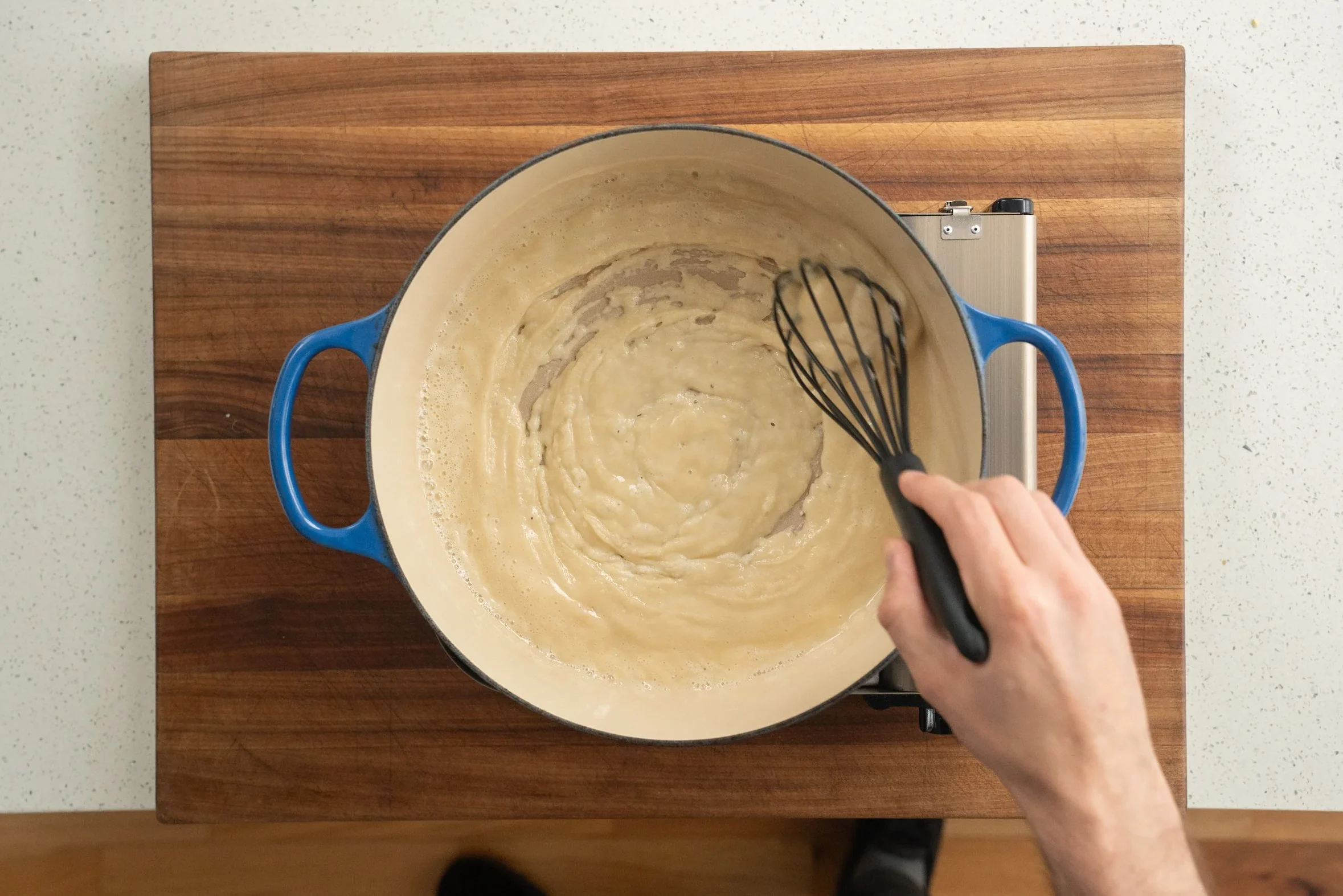 whisking oil and flour together for a roux in blue dutch oven