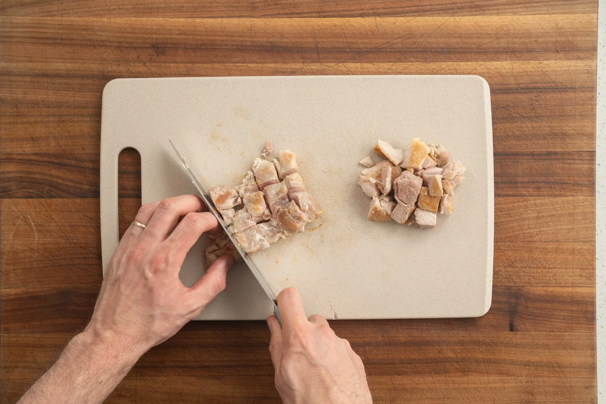 dicing chicken thighs on a cutting board