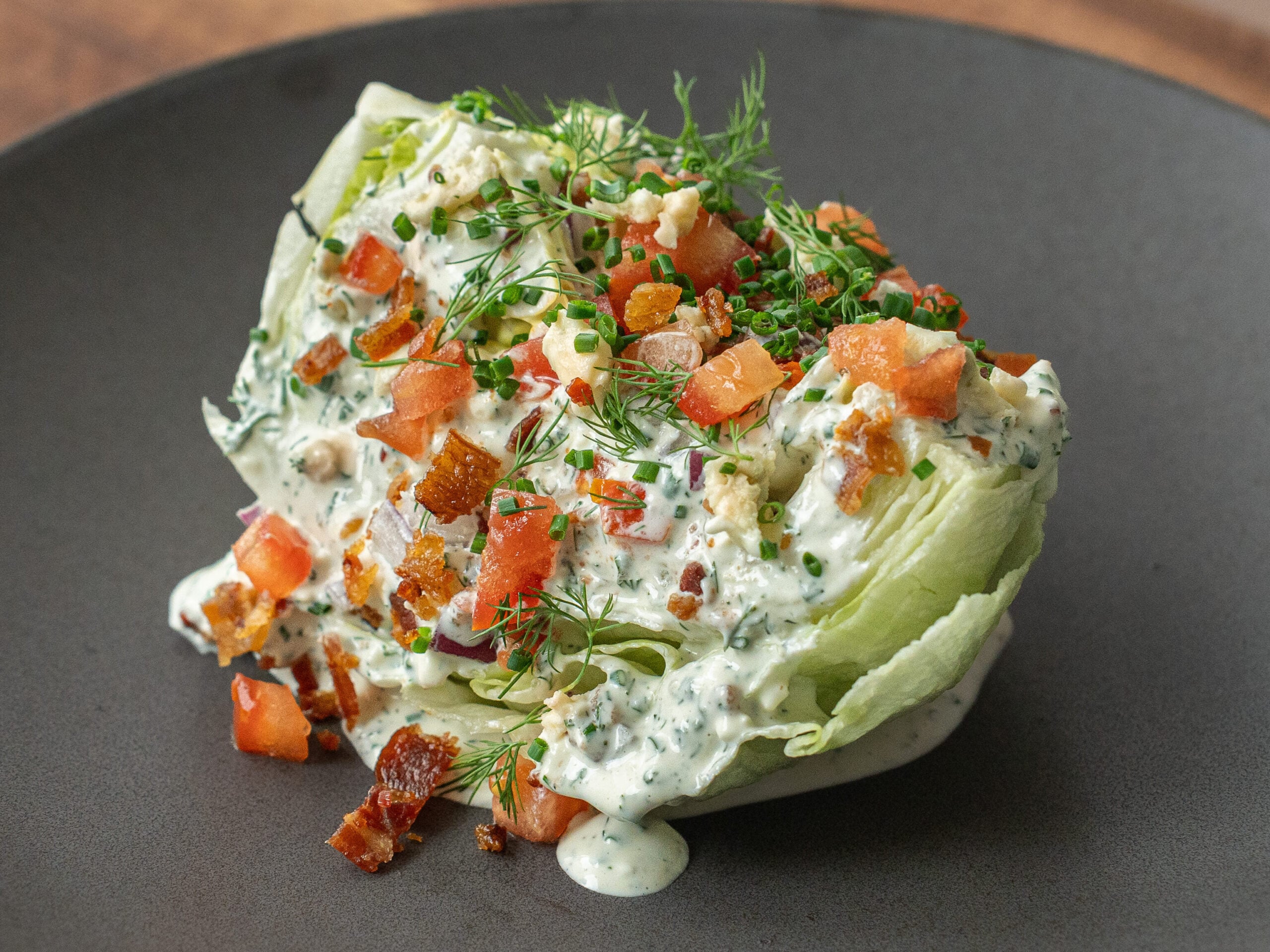 dressed wedge salad on black plate