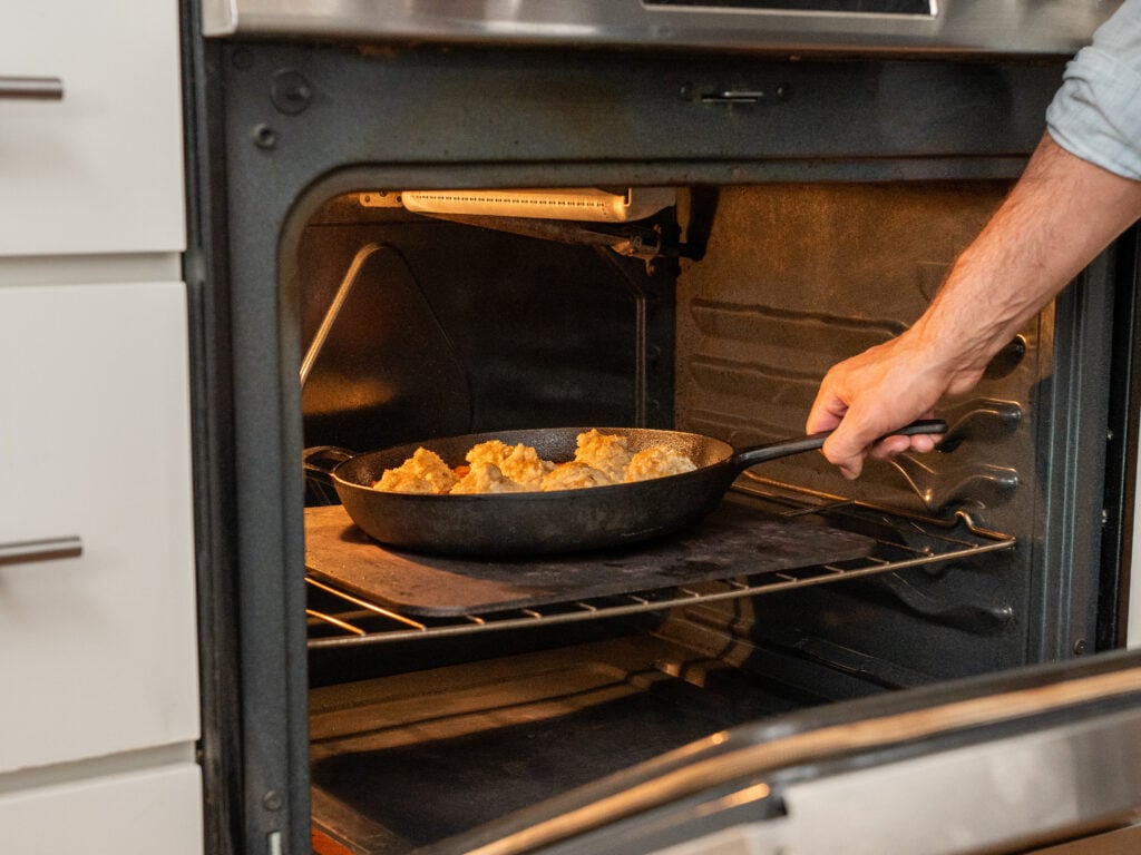 man placing pan of peach cobbler in oven