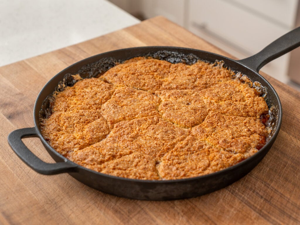 golden brown peach cobbler in cast iron skillet