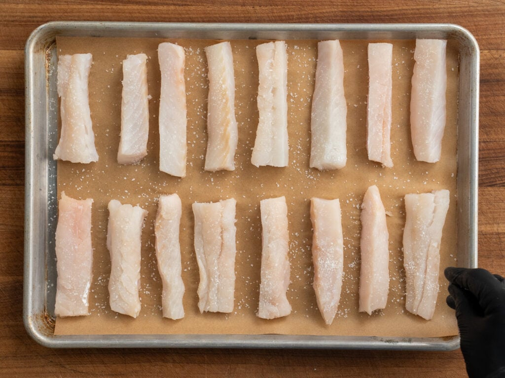 parchment lined sheet tray lined with planks of Atlantic cod