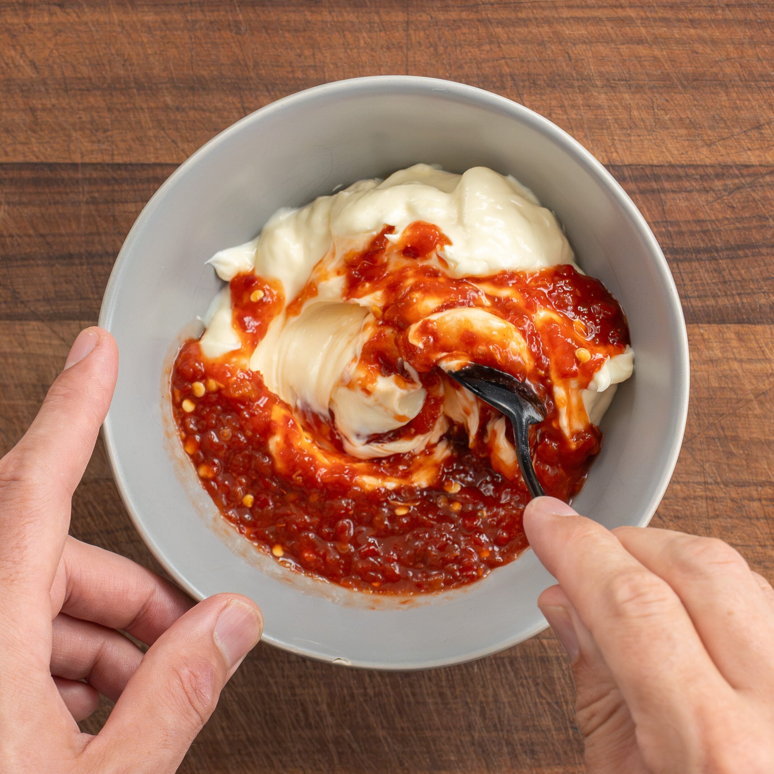 using black spoon to combine sambar and mayo in grey bowl