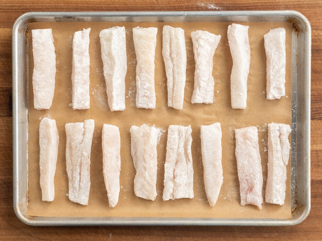 pieces of salted cod on parchment lined sheet tray