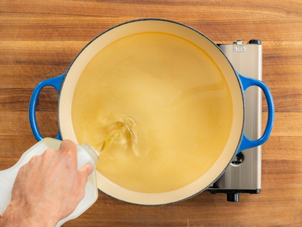hand pouring oil into blue dutch oven