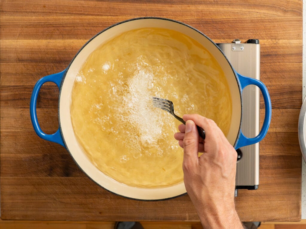 piece of battered Atlantic cod frying in dutch oven filled with oil