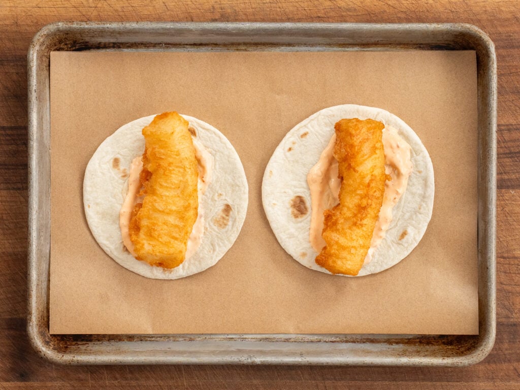 beer battered fried planks of cod sitting on 2 small flour tortillas