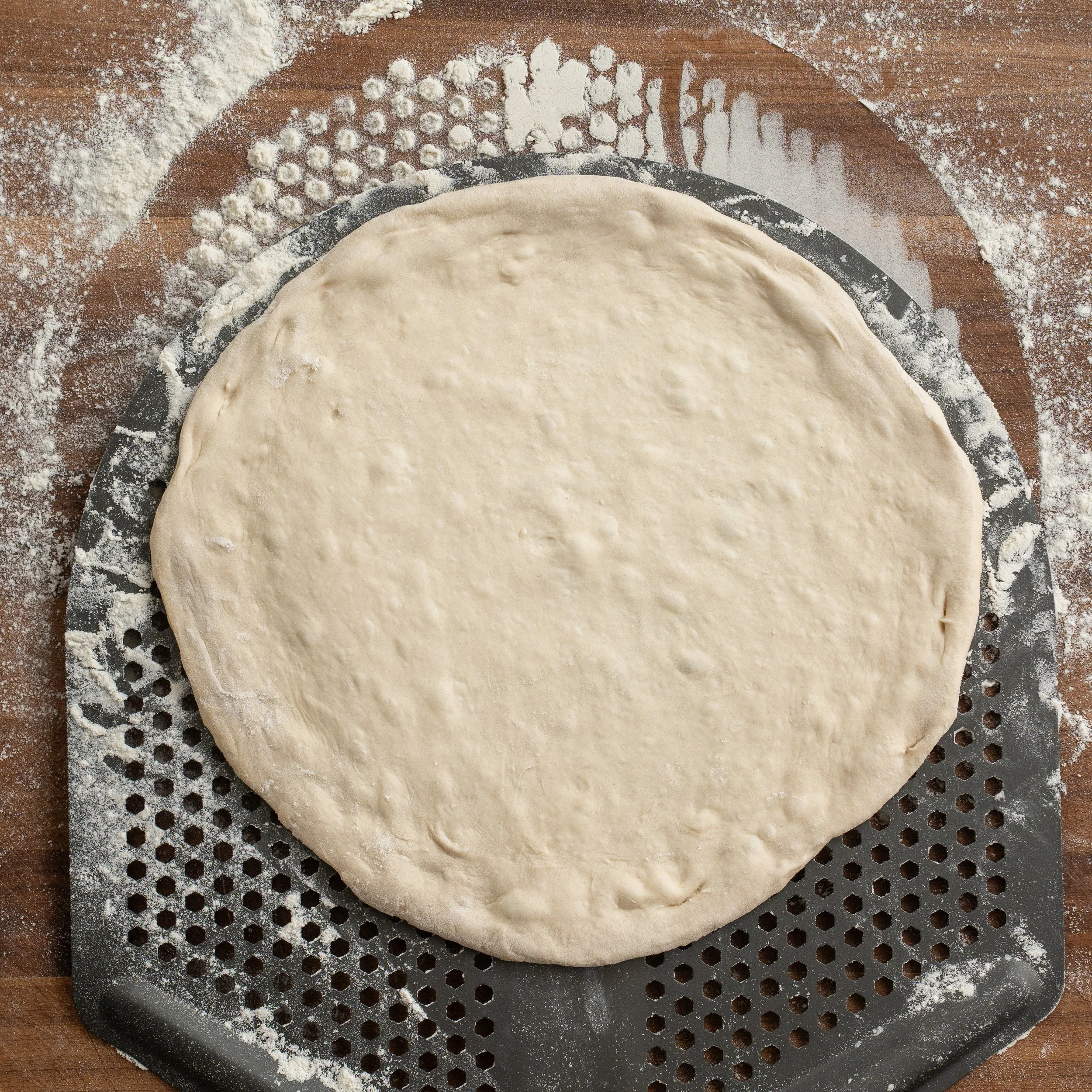 stretched pizza dough on a perforated pizza peel