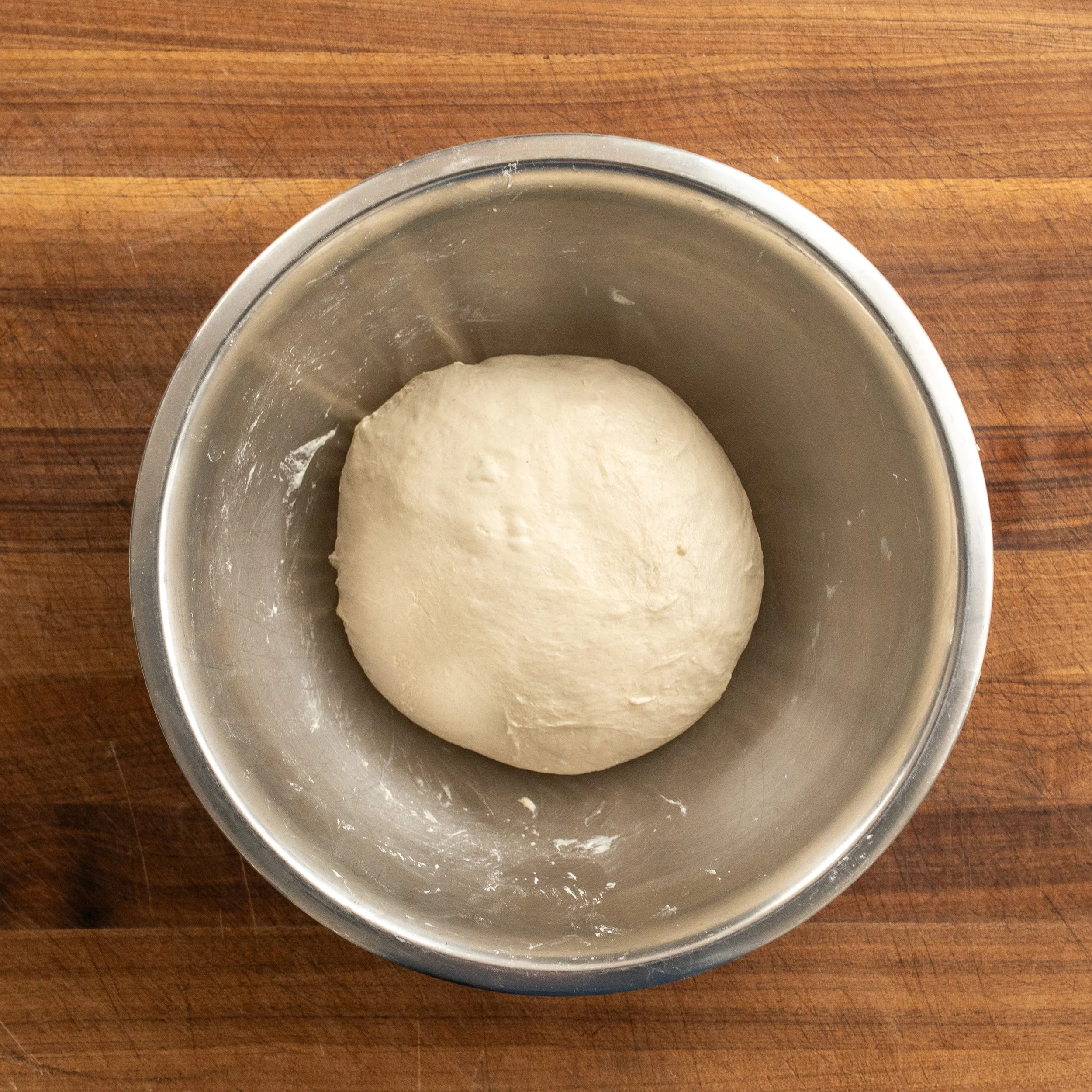 ball of pizza dough in metal bowl