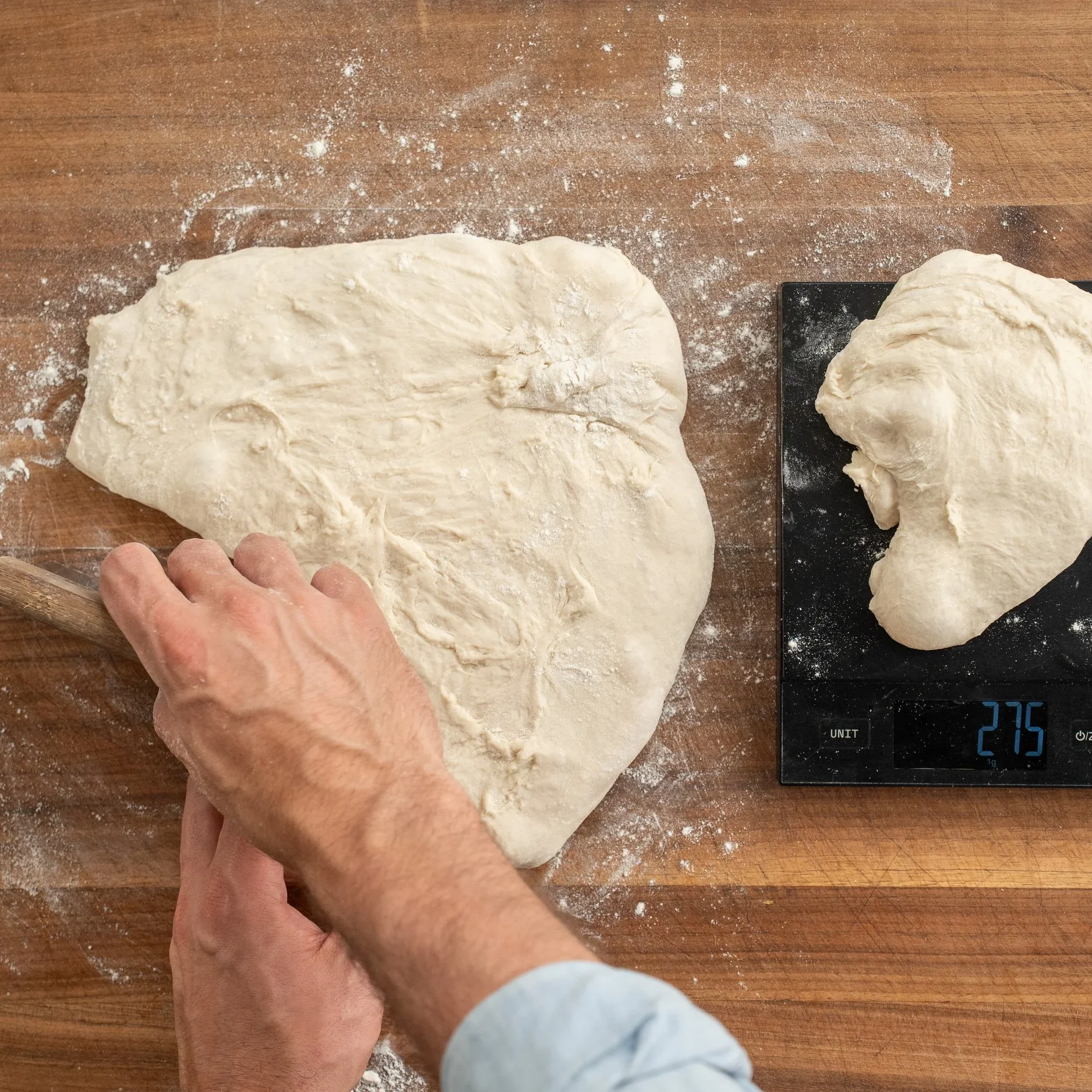 cutting and weighting out 27.5 gram dough on black kitchen scale