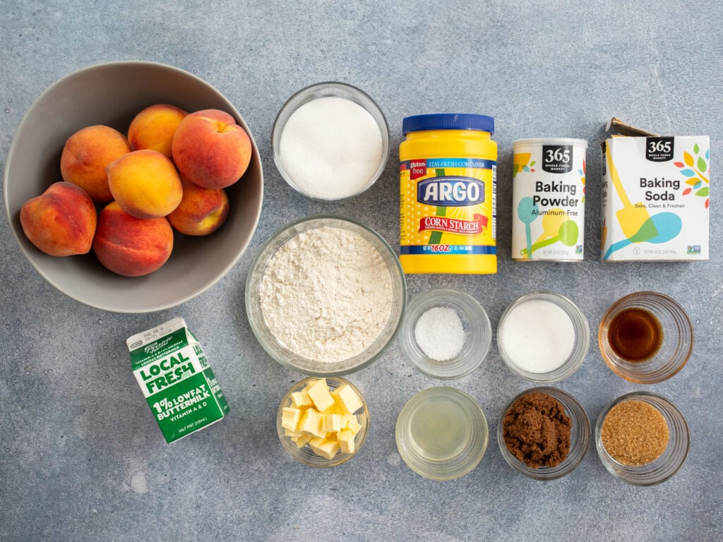 ingredients for making peach cobbler displayed on grey background