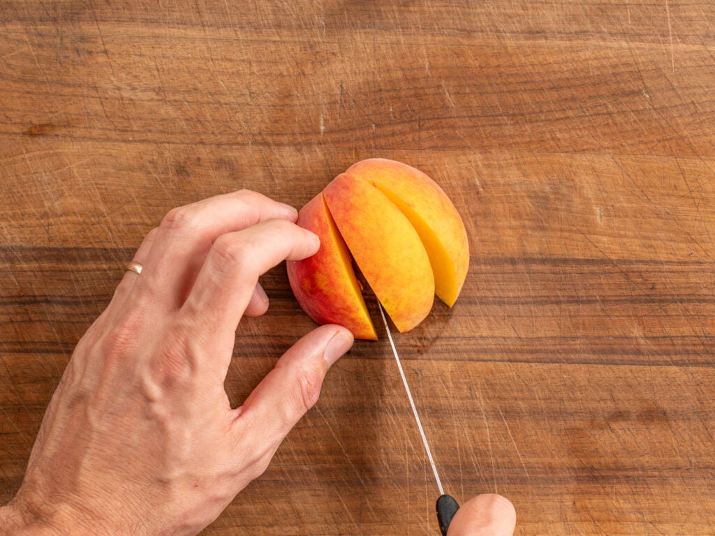 using knife to cut peach half into three slices