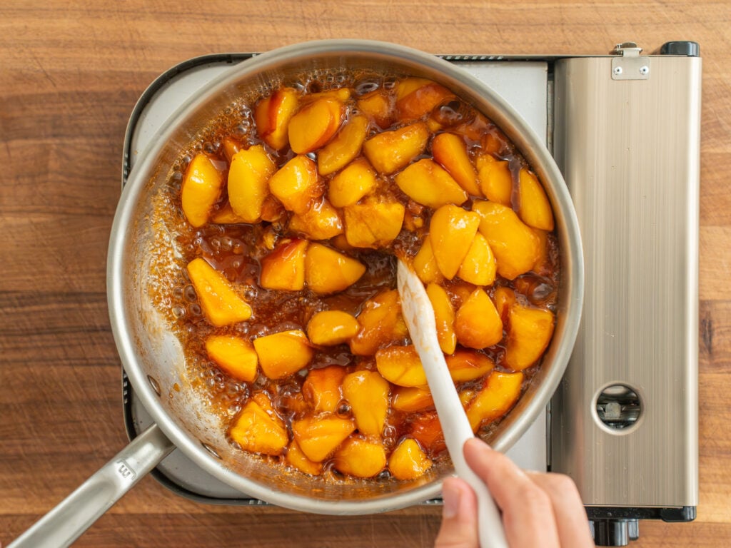 small white spatula stirring cooking peach filling