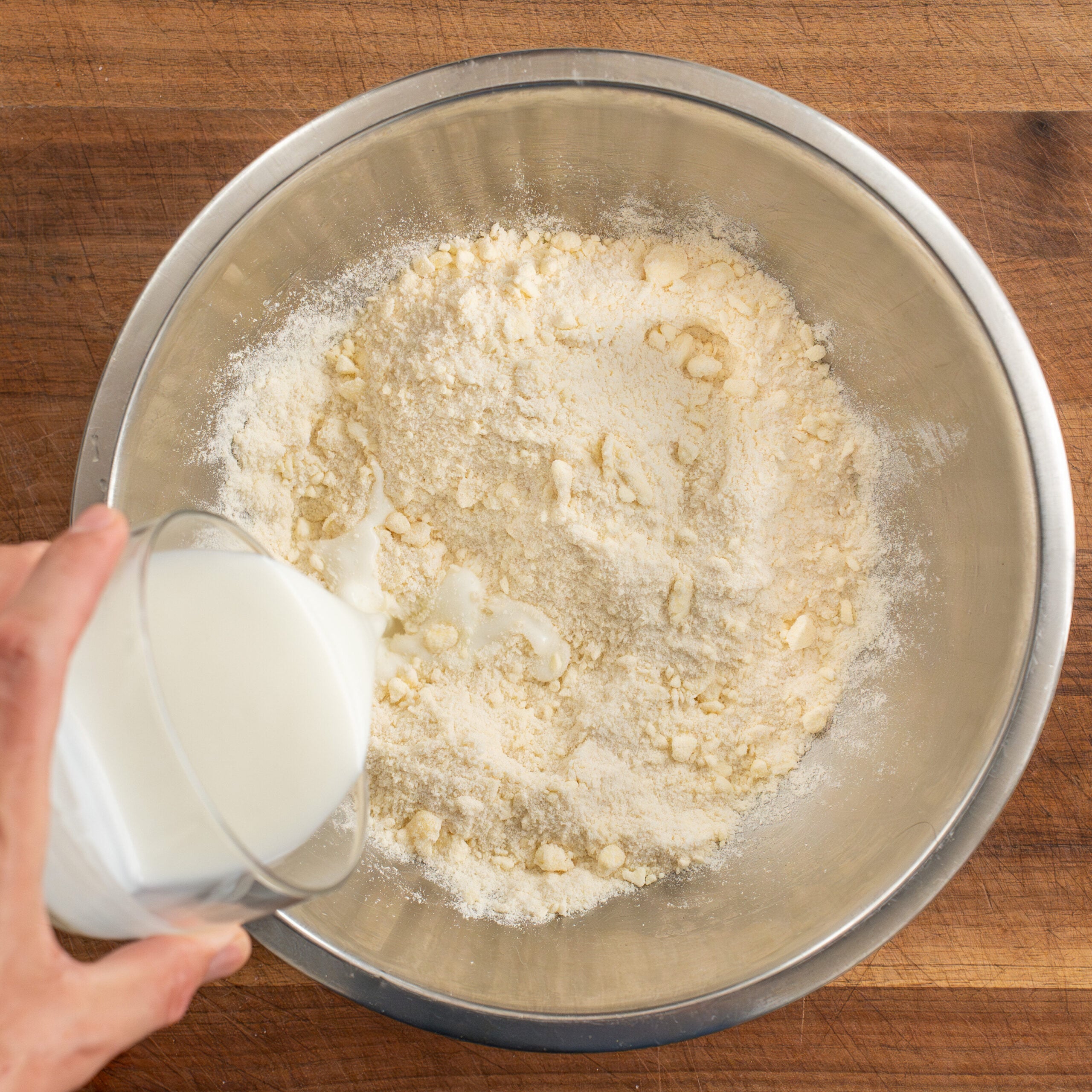 adding buttermilk to dry ingredients in silver bowl