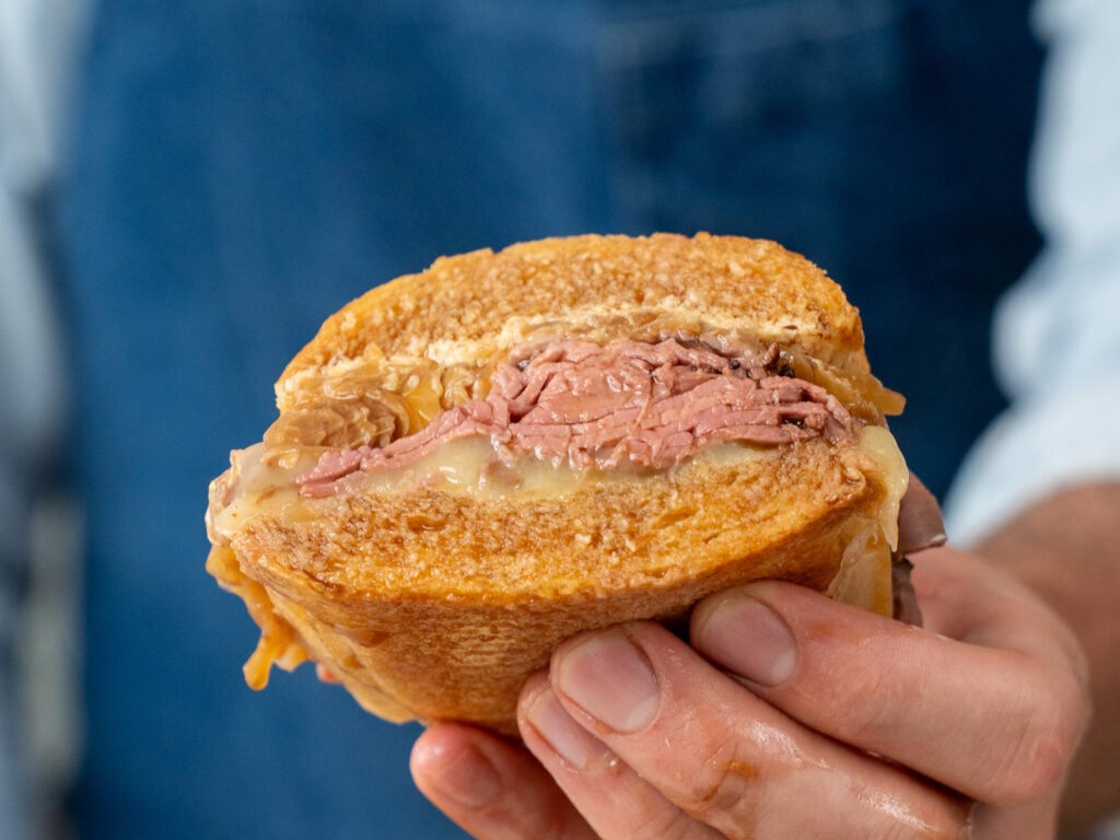 hand holding up cross section of French dip sandwich