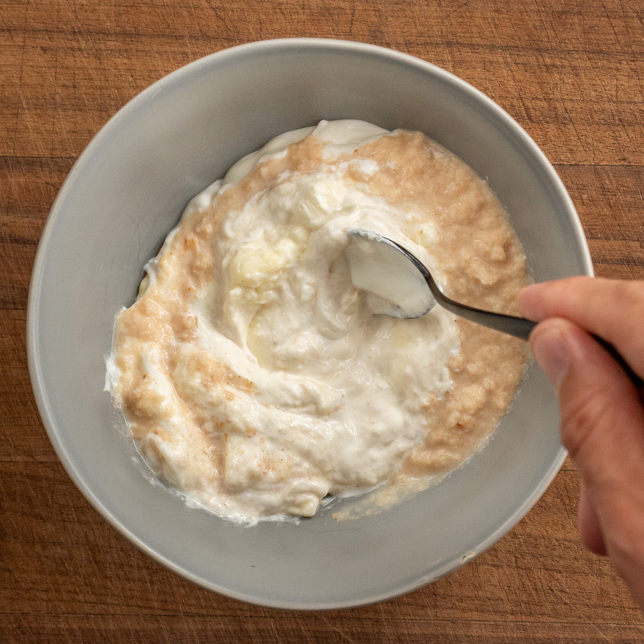 black spoon stirring together horseradish sauce in grey bowl