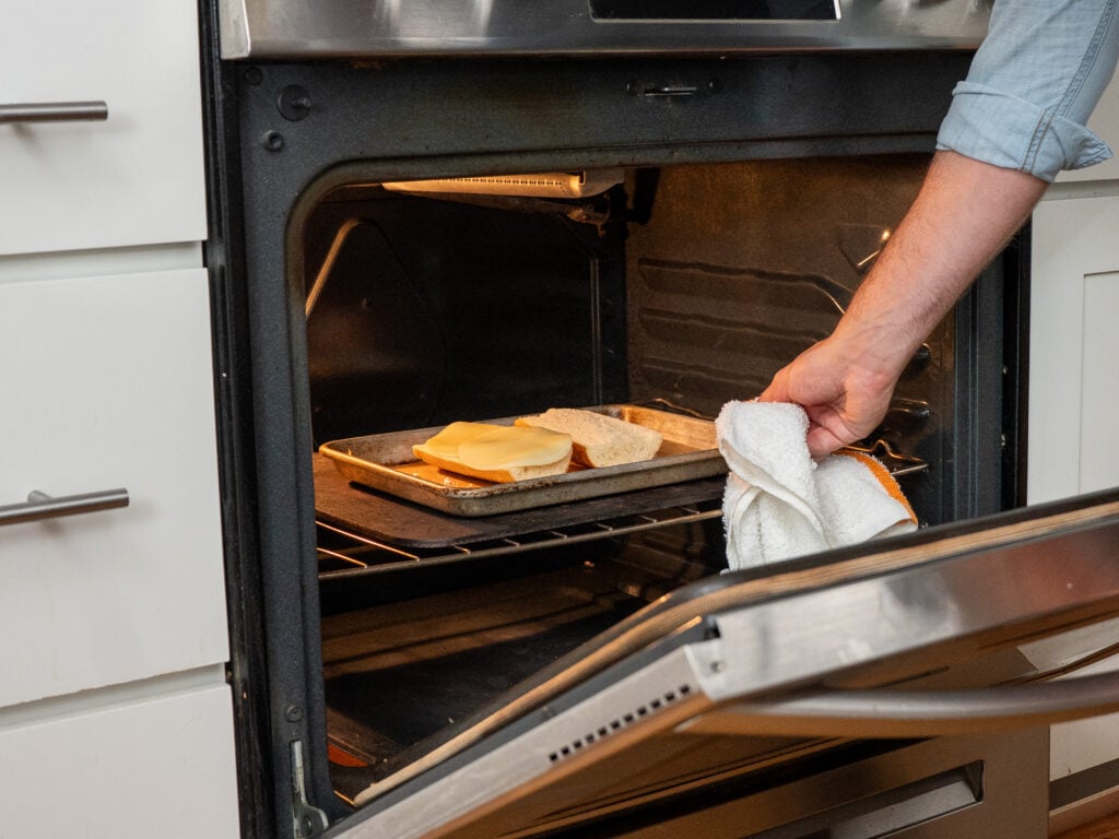 sliding sheet tray with two halves of baguette into oven