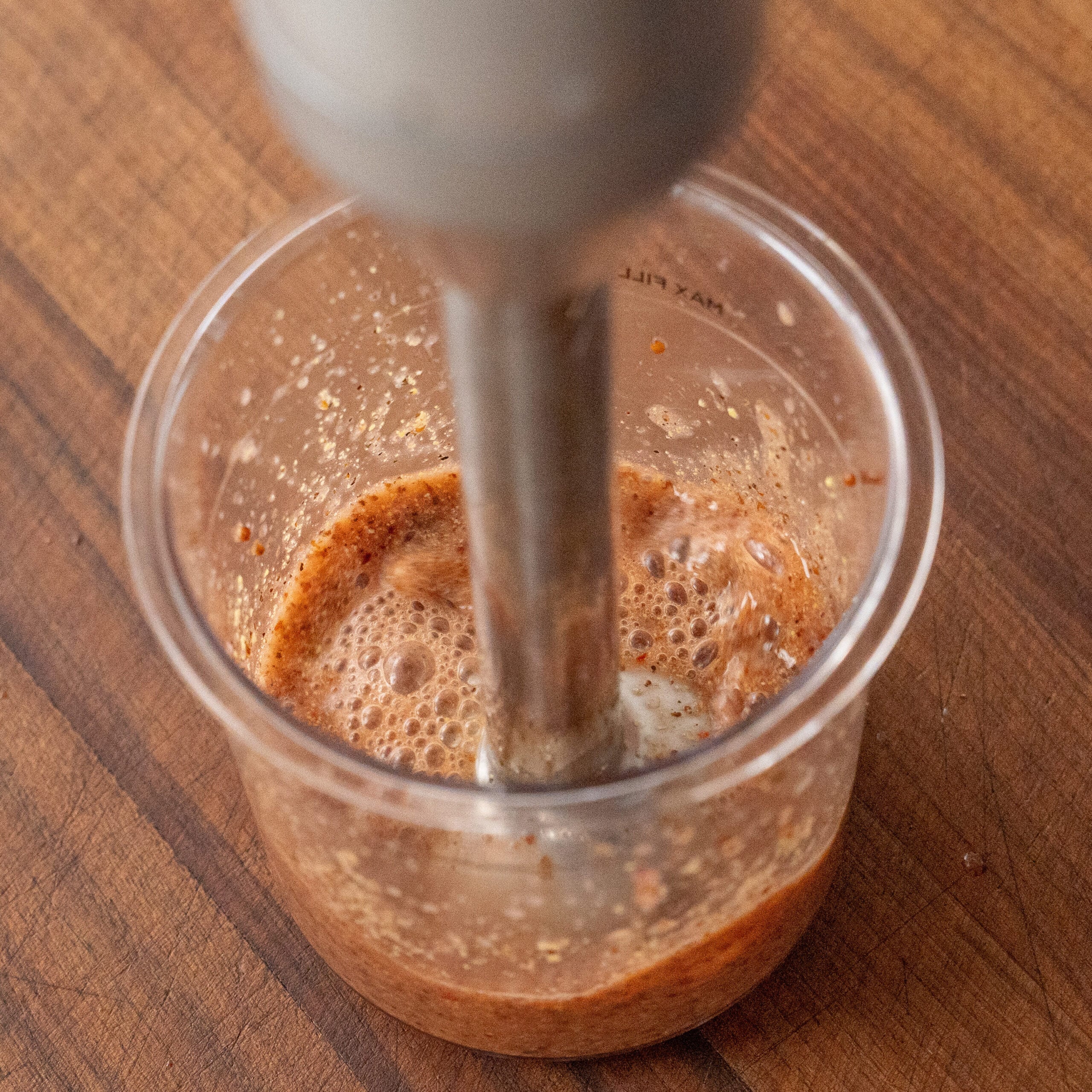 immersion blender blending Italian dressing in clear container