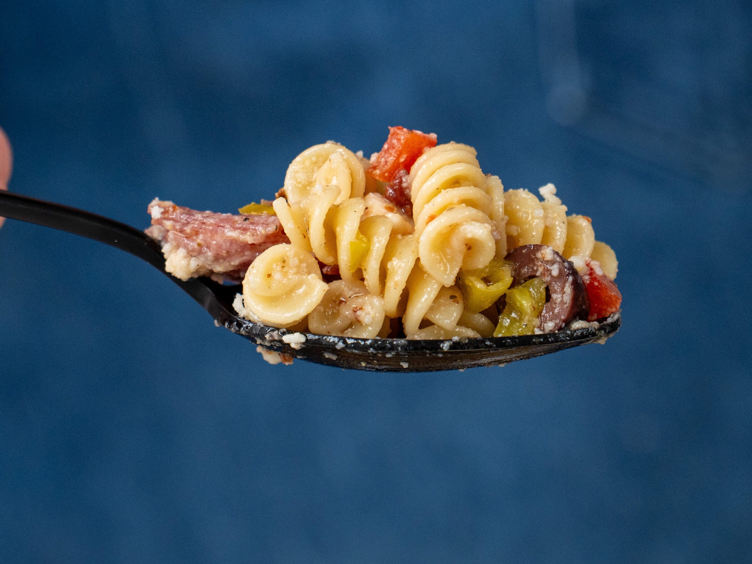 black spoon full of scoop of Italian pasta salad