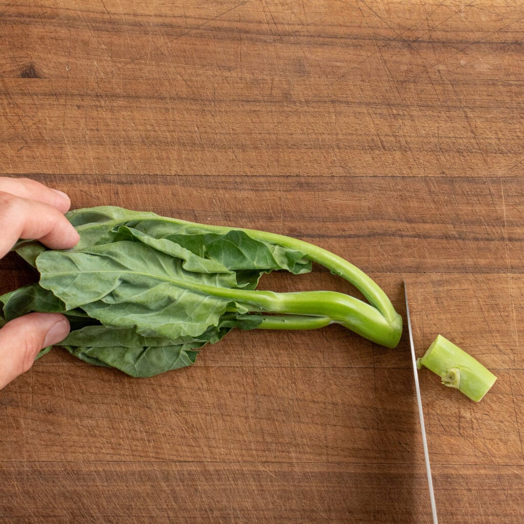 cutting stem end off Chinese broccoli in cutting board