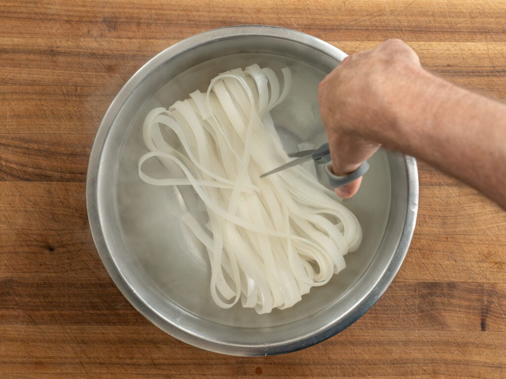 cutting rice noodles in water with scissors