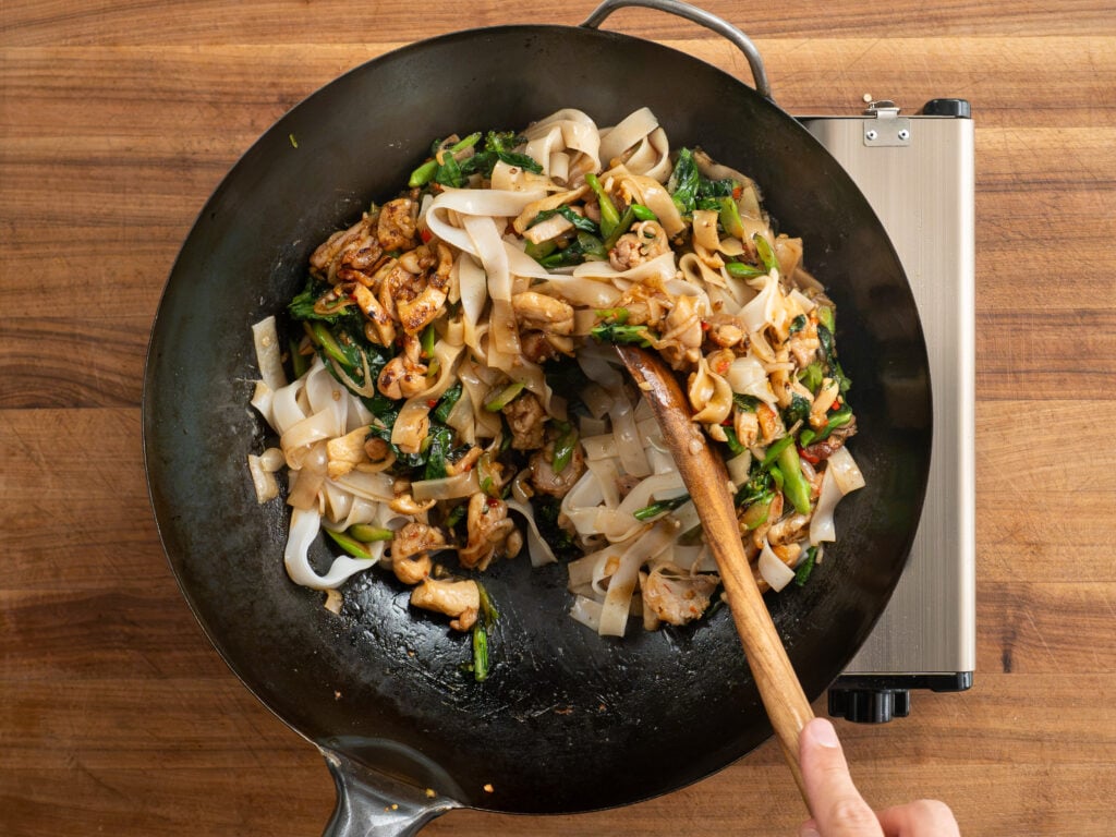 combining drunken noodle components in wok