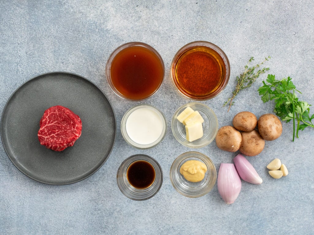 ingredients for steak diane arranged on grey surface