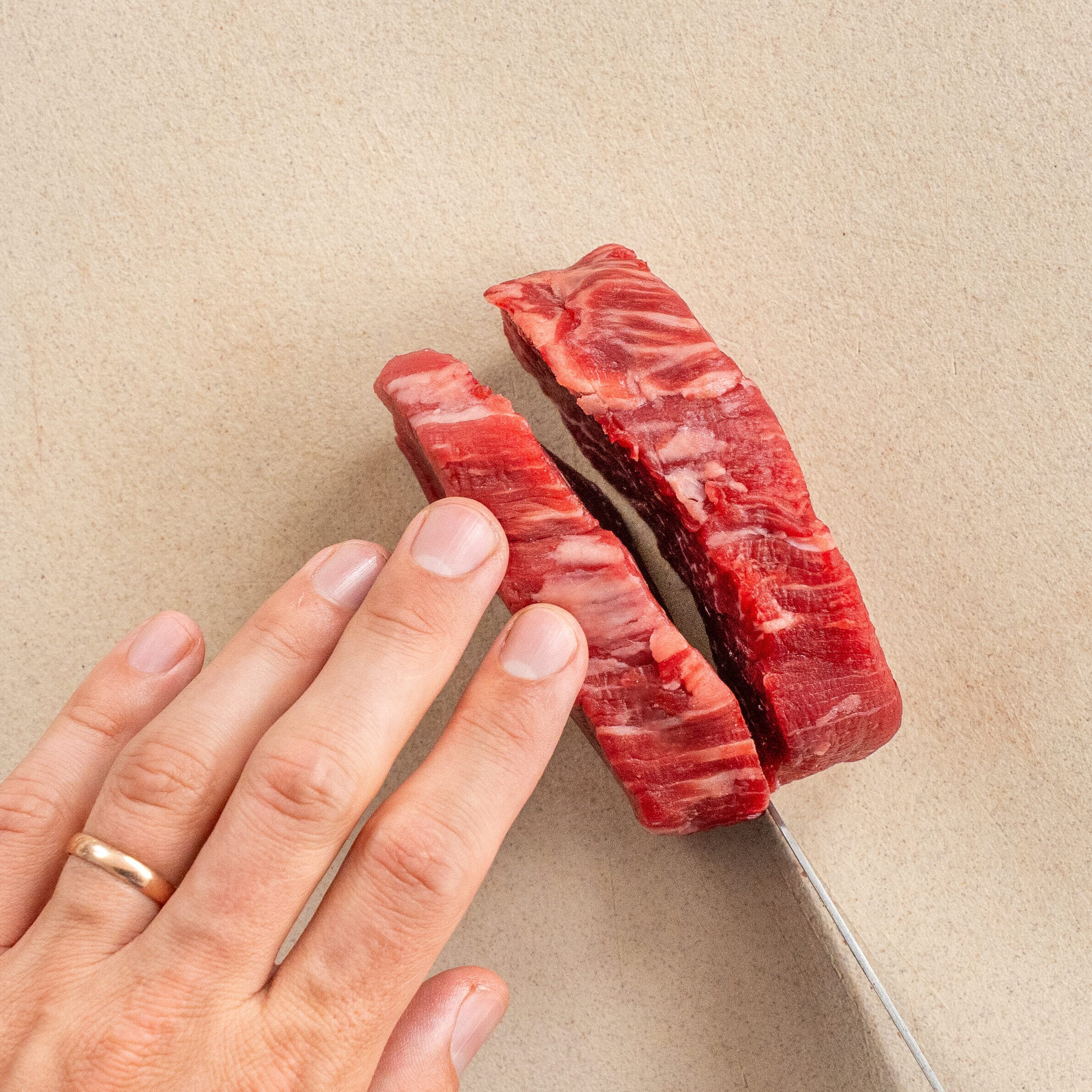 knife slicing through raw filet mignon