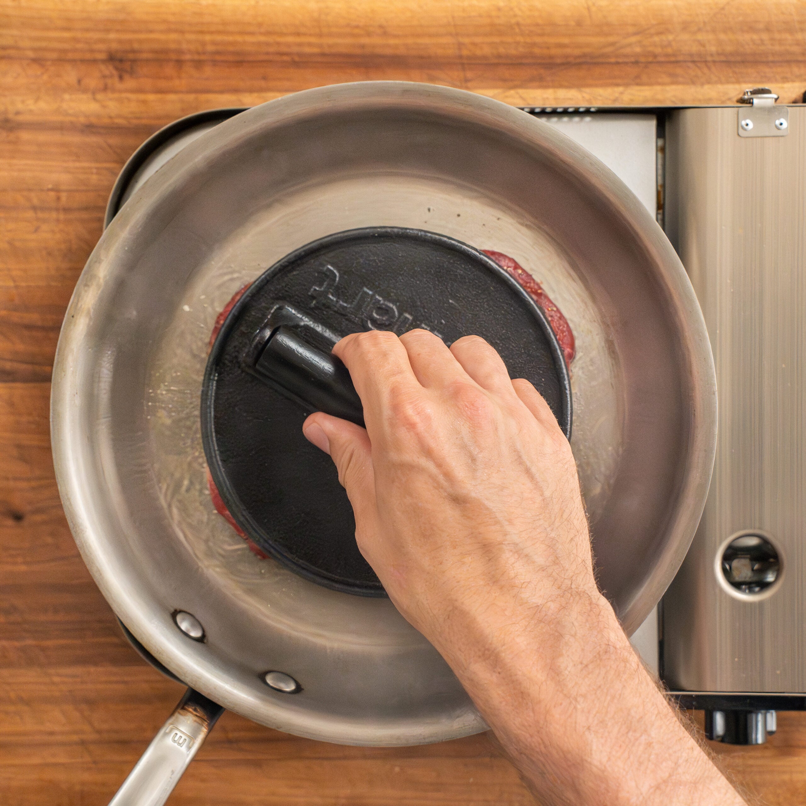 pressing steak into saute pan using meat weight