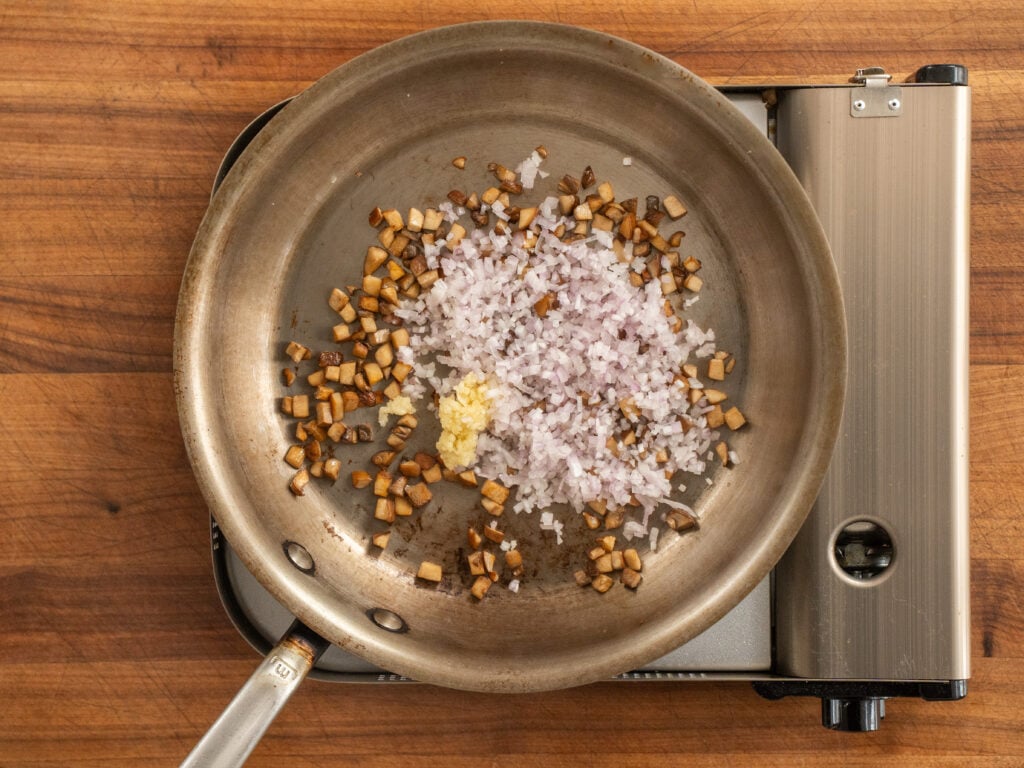 sautéed mushrooms with raw shallot and garlic in a saute pan
